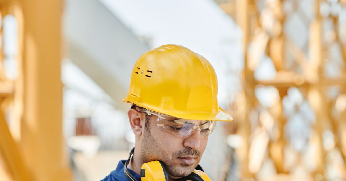 Construction worker in a hard hat reviewing plans at a job site