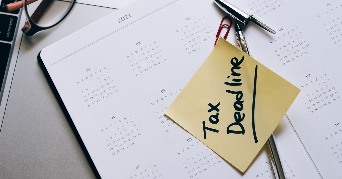 Tax deadline reminder on a planner beside a laptop and tax documents